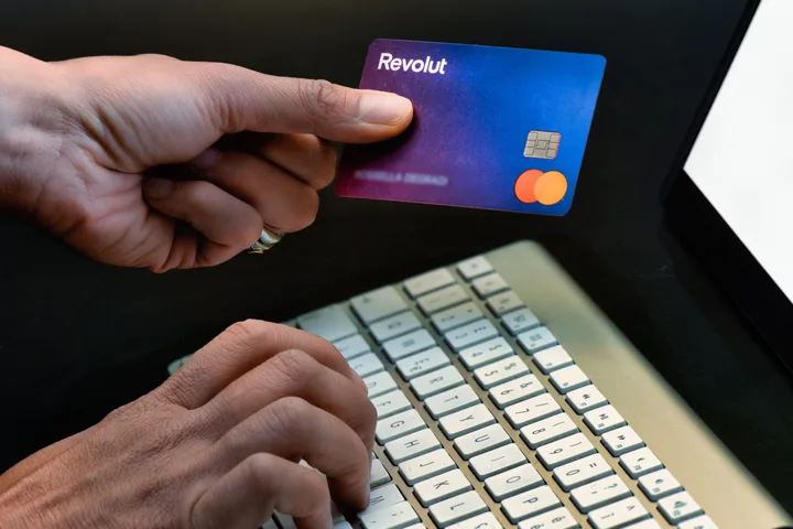 Card Revolut utilizat pentru plăți online, alături de un laptop.