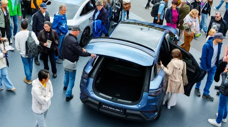 Oameni admirând un vehicul electric BYD la un eveniment auto.