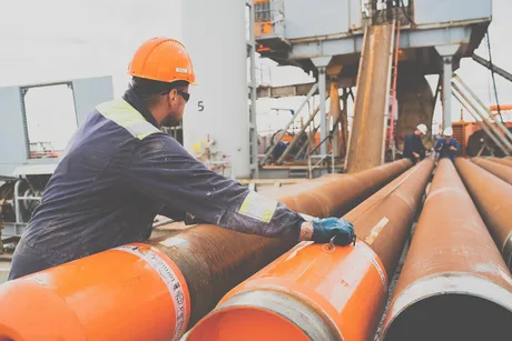 Un muncitor inspectează conducte pentru gaze naturale la un terminal.