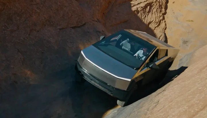 Tesla Cybertruck traversând un teren accidentat, evidențiind designul său robust.