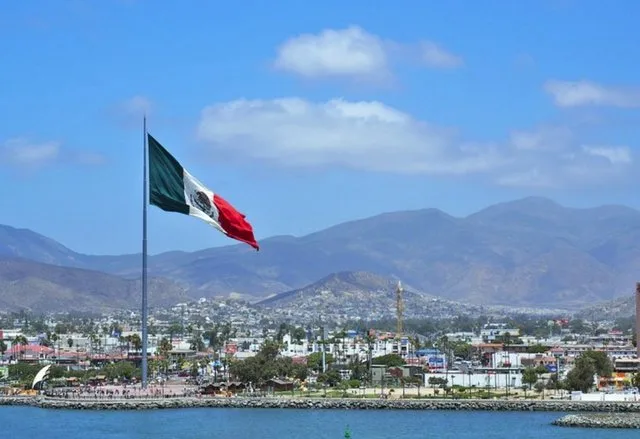 Steagul Mexicului fluturând pe fundalul unui peisaj montan.