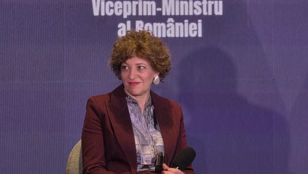 Oana Gheorghiu zâmbind la o conferință, discutând despre reforme.