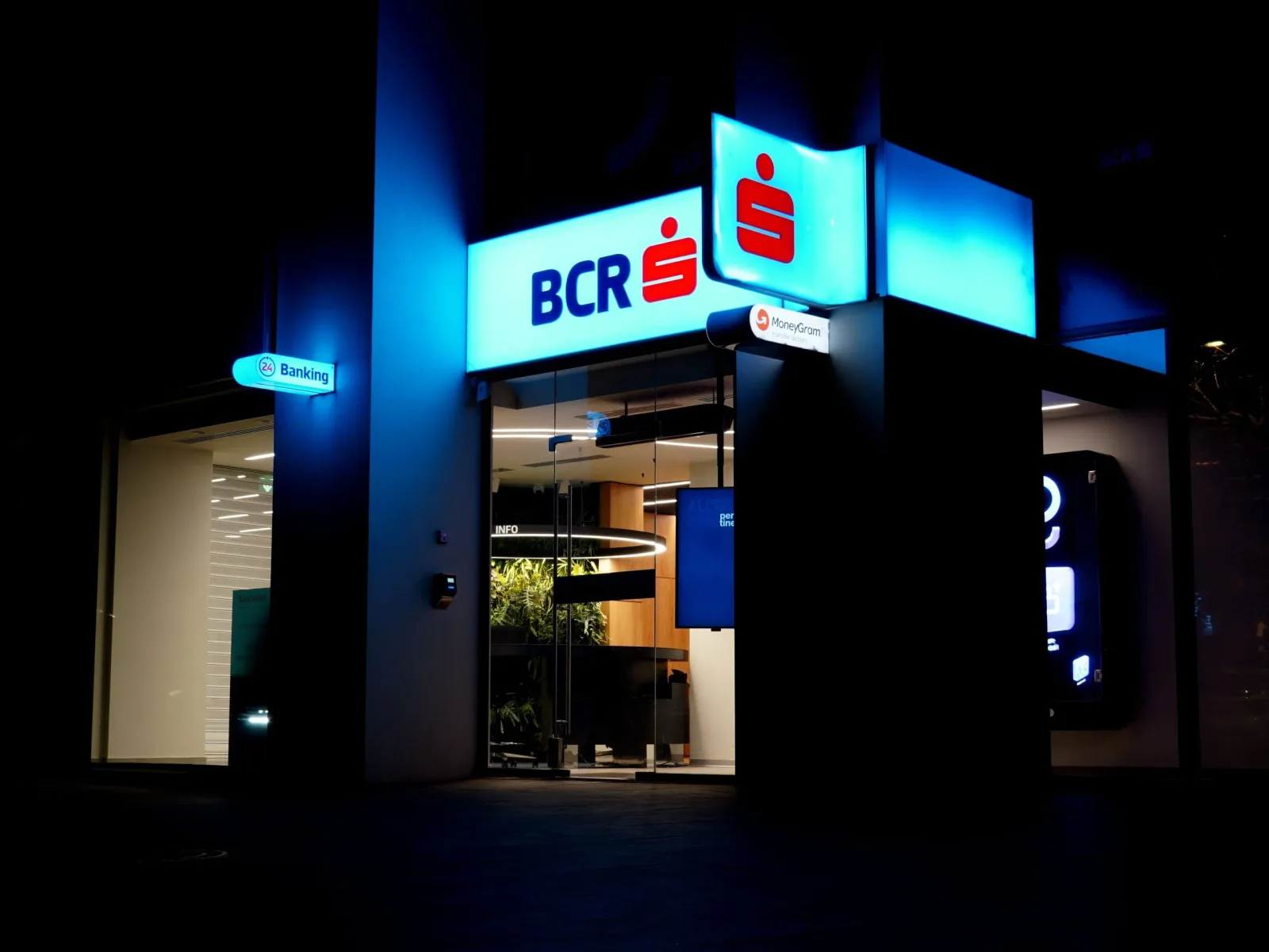 Sediul BCR iluminat noaptea, cu logo-ul băncii vizibil.