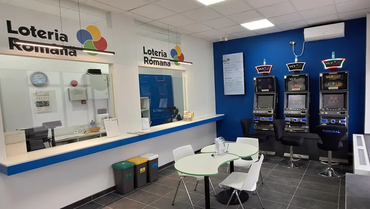Spațiu dedicat jocurilor de noroc la Loteria Română, cu aparate și mese.