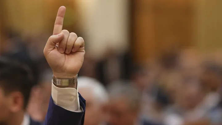Un deget ridicat în semn de vot în cadrul unei ședințe oficiale.