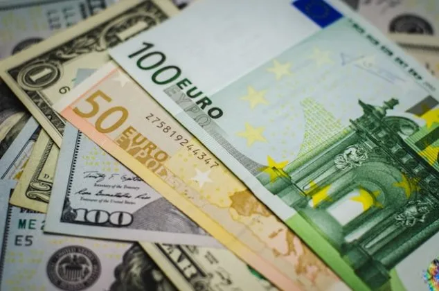 Bancnote de euro și dolari așezate împreună pe o suprafață.