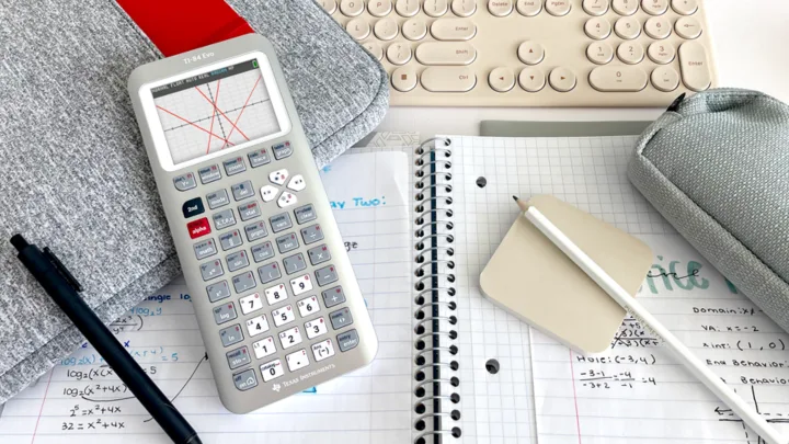 Calculator grafic TI-84 Evo pe birou, alături de caiete și instrumente de scris.
