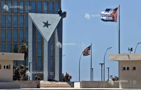 Clădiri simbolice din Cuba, cu steagul național și cel american în fundal.