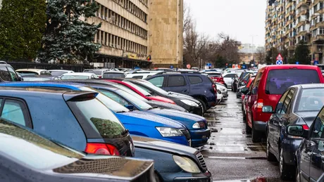 Parcări aglomerate pe o stradă din București, cu mașini parcate pe trotuar.