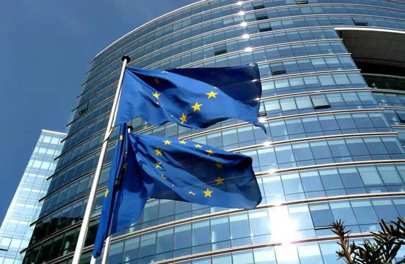 Steagurile Uniunii Europene fluturând în fața unei clădiri moderne.