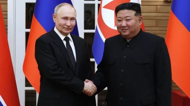 Kim Jong-un și Vladimir Putin la o întâlnire oficială, sub steagurile celor două țări.