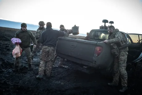 Soldați ucraineni discutând în apropierea unui vehicul pe un teren mlăștinos.