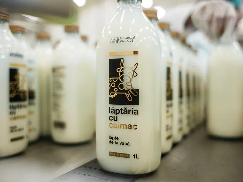 Sticle de lapte de la Lăptăria cu Caimac pe un raft.