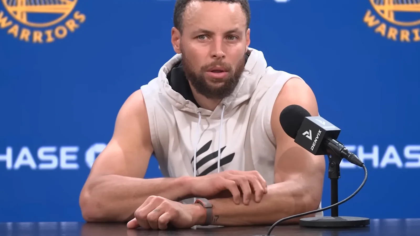 Stephen Curry discutând despre un dispozitiv Fitbit fără ecran la o conferință de presă.