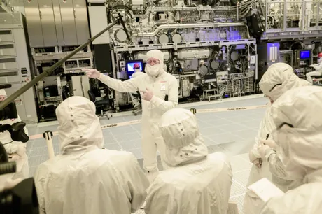 Specialiști discutând despre tehnologia High-NA EUV în fabrică.