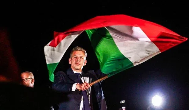 Peter Magyar fluturând steagul Ungariei la un eveniment public.