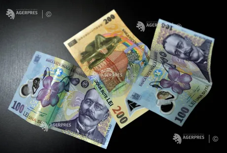 Bancnote românești de diferite valori așezate pe o suprafață întunecată.