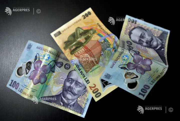 Bancnote românești de diferite valori așezate pe o suprafață întunecată.