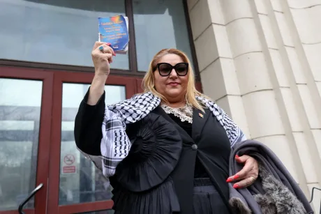 Diana Șoșoacă ține un document în fața unei clădiri oficiale.