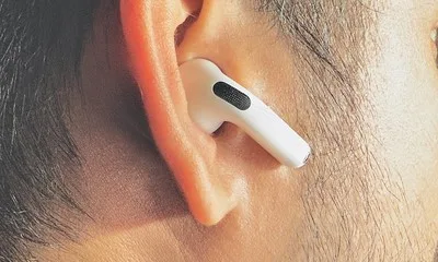 Căști AirPods albe, purtate într-o ureche, cu un design modern.