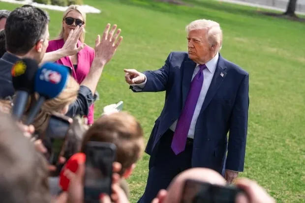 Donald Trump interacționează cu jurnaliști pe un teren verde.