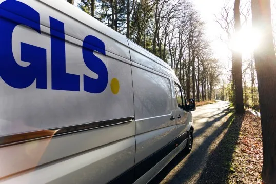 Furgoneta GLS pe un drum forestier, simbolizând creșterea în logistică.