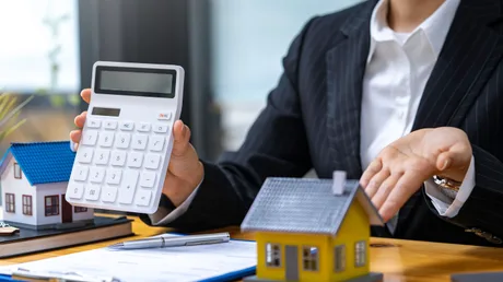 Persoana discută despre impozitele pe proprietate, având un calculator și case miniaturale.