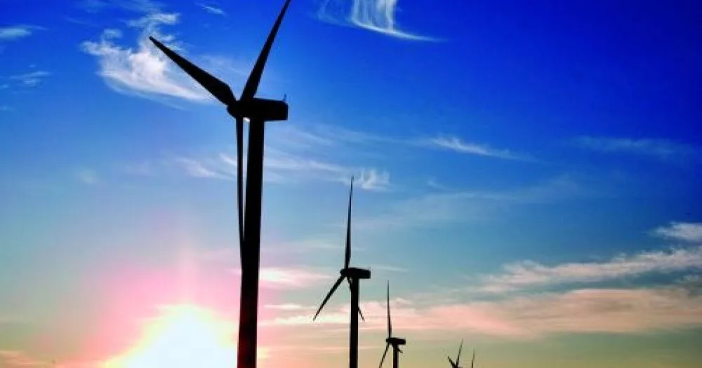 Turbine eoliene în lumina apusului, simbolizând energia regenerabilă.