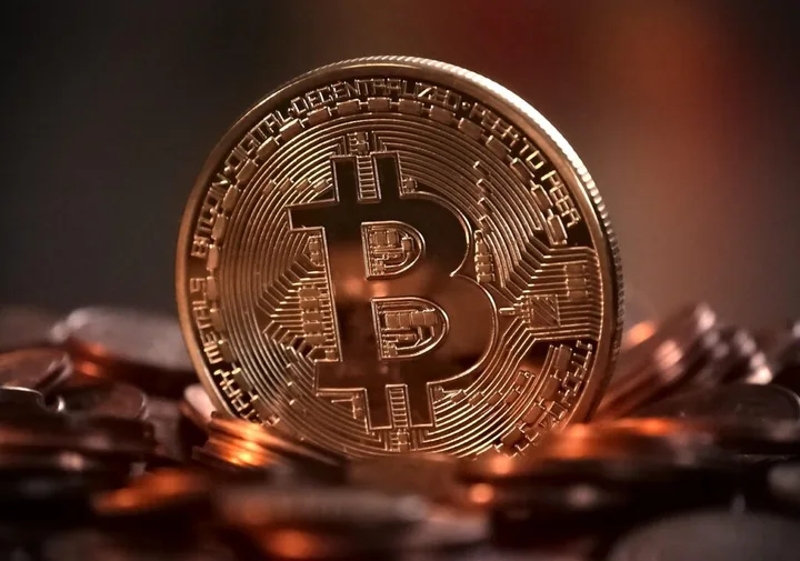 Monedă Bitcoin strălucitoare pe un fundal de monede.