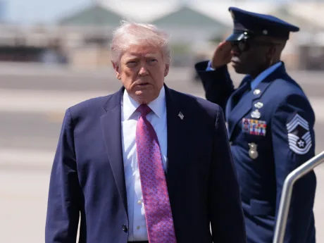 Donald Trump în timpul unei vizite oficiale, cu un soldat în fundal.