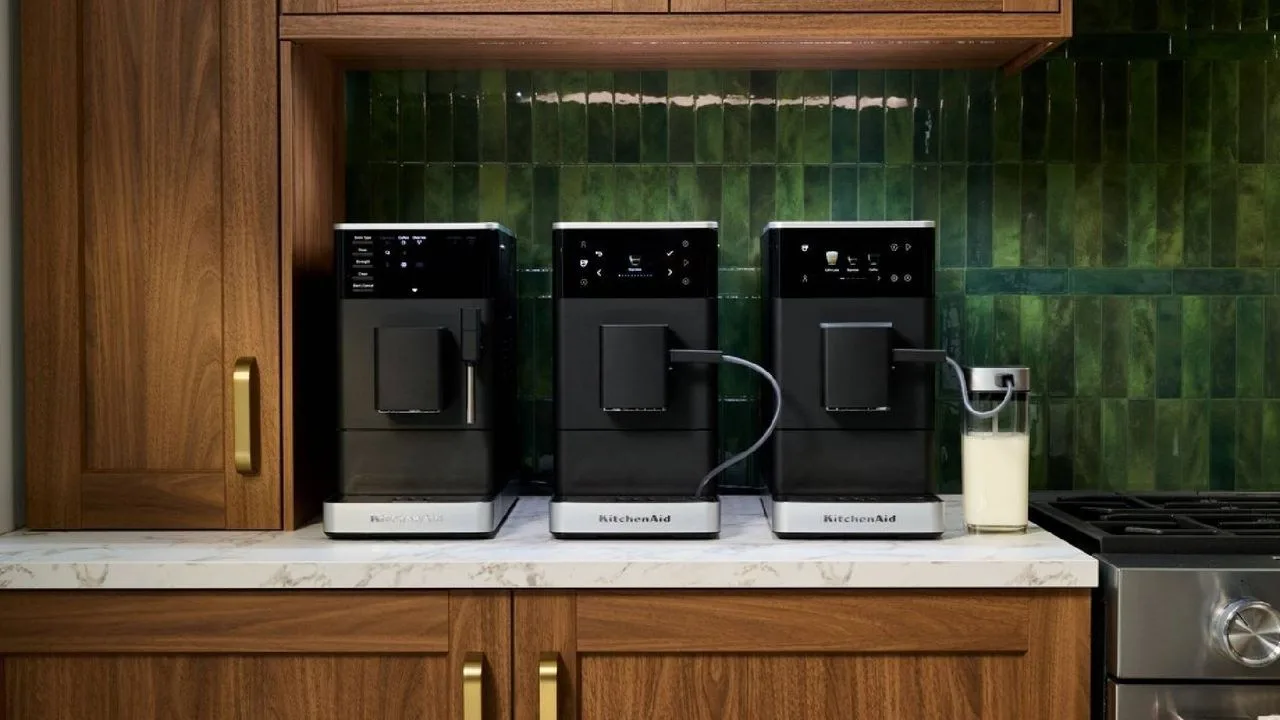 Trei espressoare automate KitchenAid pe un blat de bucătărie modern.