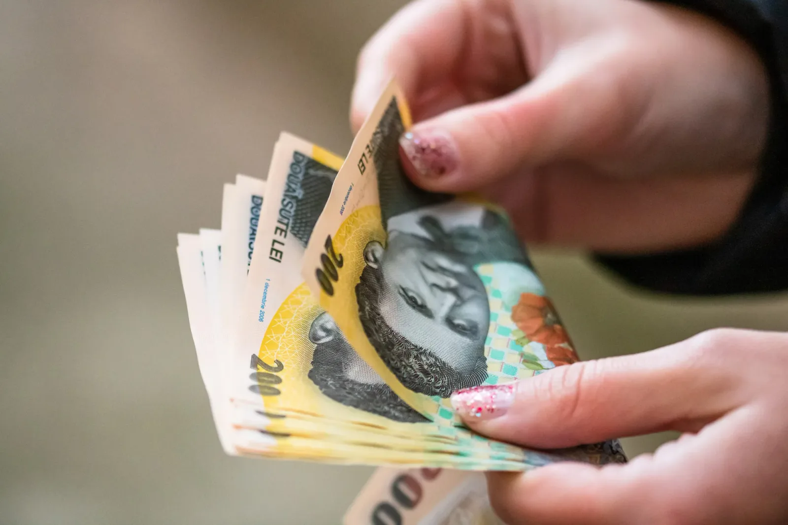 Bancnote de lei în mâinile unei persoane, simbolizând câștigurile salariale.