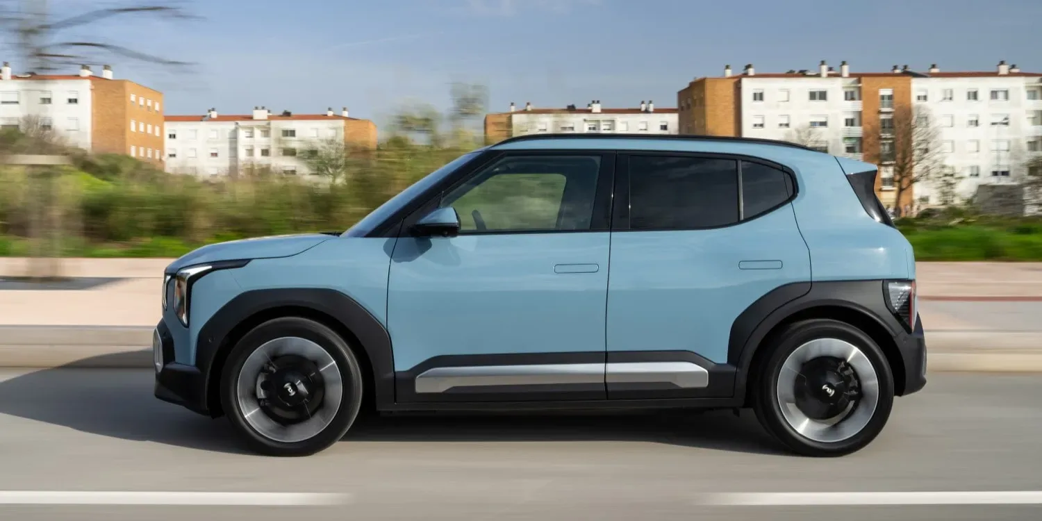 SUV electric Kia EV2, disponibil în mai multe culori, pe drum, cu clădiri în fundal.