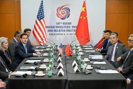 Discuții diplomatice între oficiali americani și chinezi la o masă de negocieri.