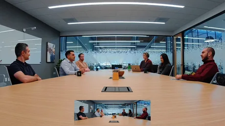 Discuție într-o sală de ședință modernă, cu participanți la videoconferință.