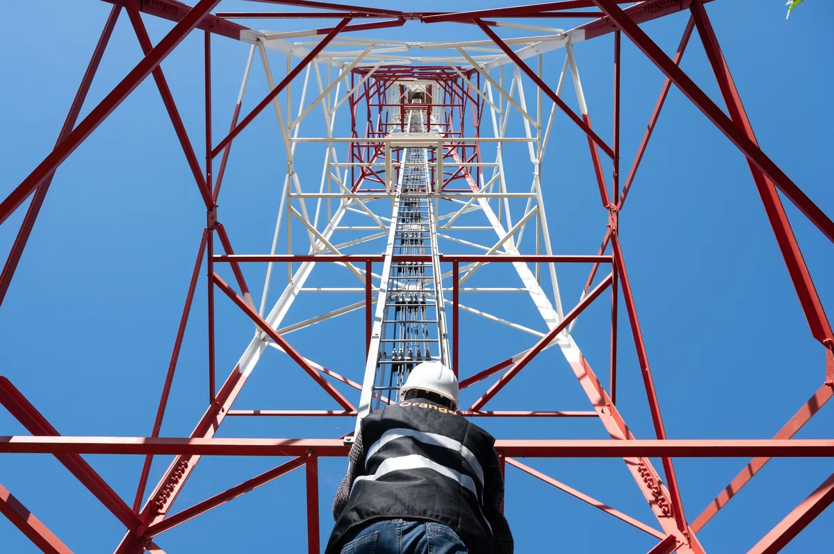 Tehnician urcând pe un stâlp de telecomunicații pentru extinderea rețelei 5G