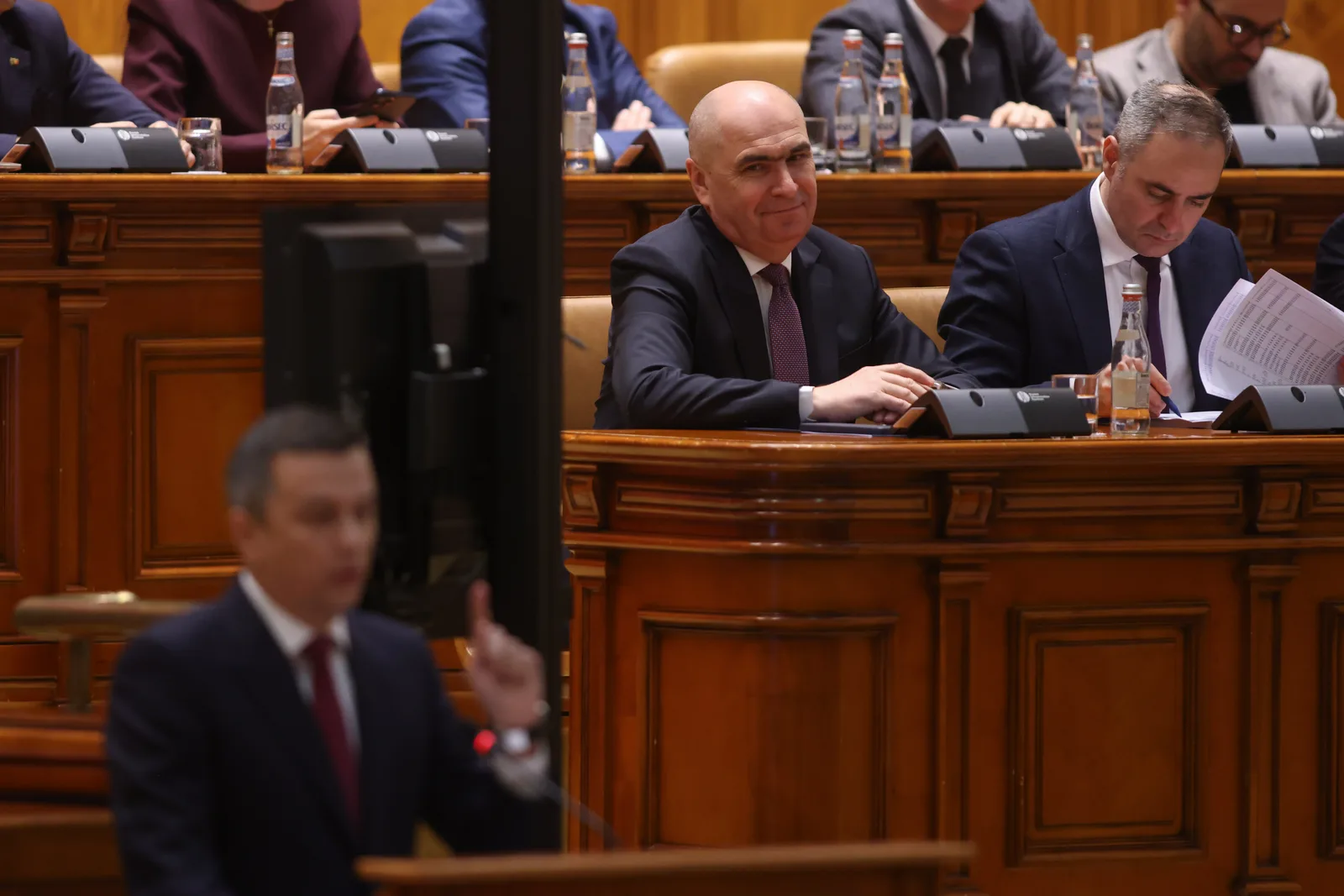 Parlamentarii discută despre moțiunea de cenzură în sala de ședințe.