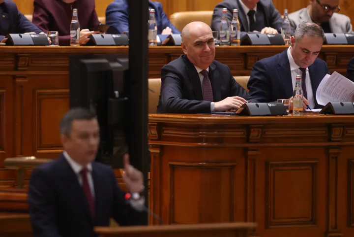Parlamentarii discută despre moțiunea de cenzură în sala de ședințe.