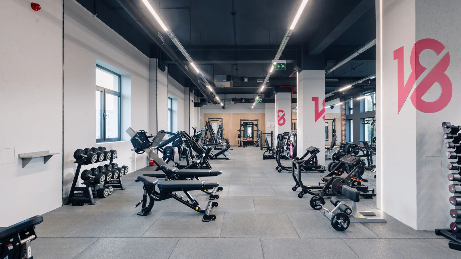 Spațiu modern de fitness cu echipamente variate și iluminare naturală.