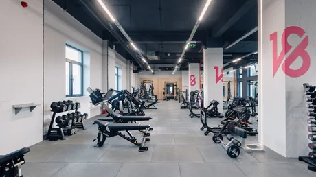 Spațiu modern de fitness cu echipamente variate și iluminare naturală.