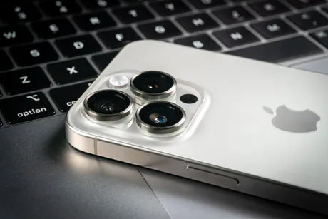 Detaliu al camerei unui smartphone Apple pe un fundal de laptop.