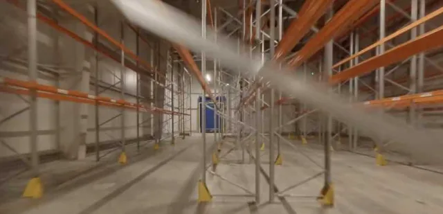 Interiorul unui depozit frigorific în construcție, cu rafturi metalice și iluminare.