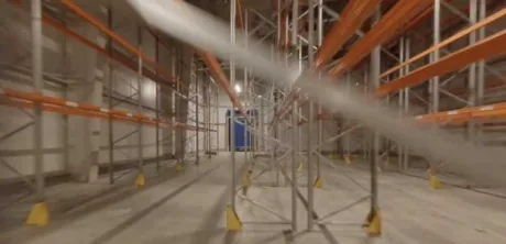 Interiorul unui depozit frigorific în construcție, cu rafturi metalice și iluminare.