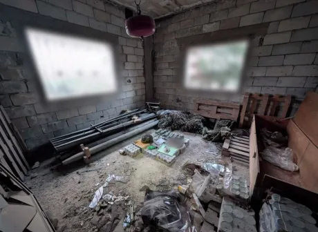 Un interior dezordonat cu materiale și echipamente militare abandonate.