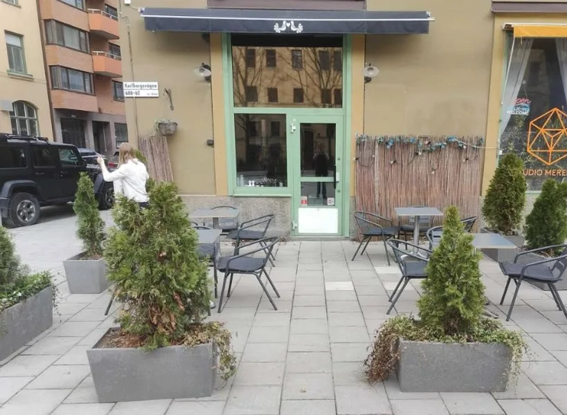 Cafeneaua din Stockholm cu mese și plante decorative în față.