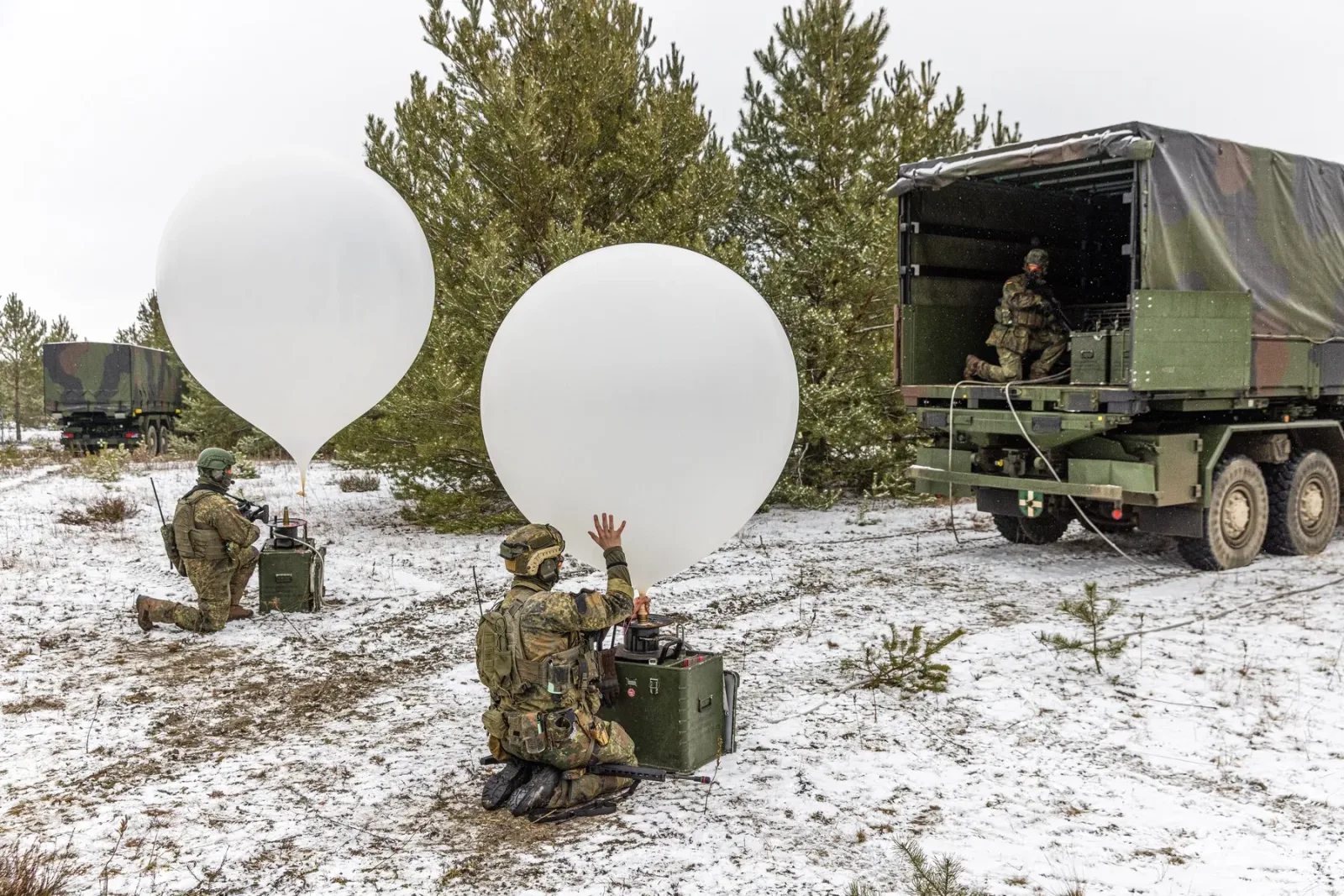 Soldați pregătesc baloane în pădure, în condiții de iarnă.