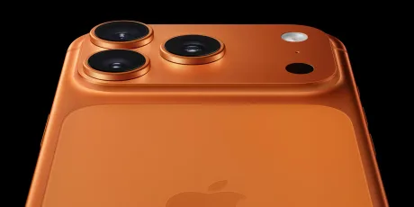 Detaliu al camerei unui iPhone 17 de culoare portocalie.