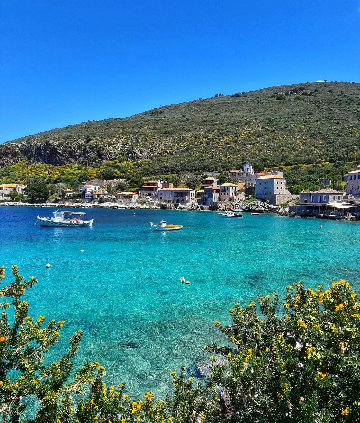 Peisaj idilic din Grecia, cu ape cristaline și case tradiționale.