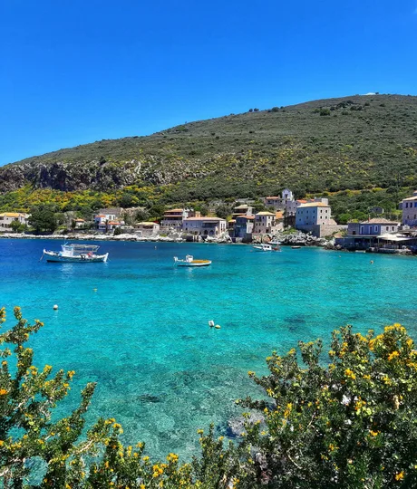 Peisaj idilic din Grecia, cu ape cristaline și case tradiționale.