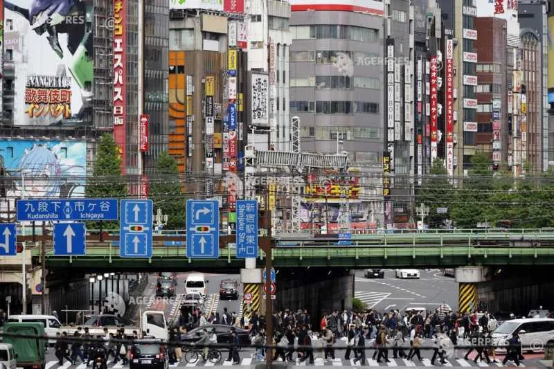 O stradă aglomerată dintr-un oraș japonez, plină de reclame și oameni.